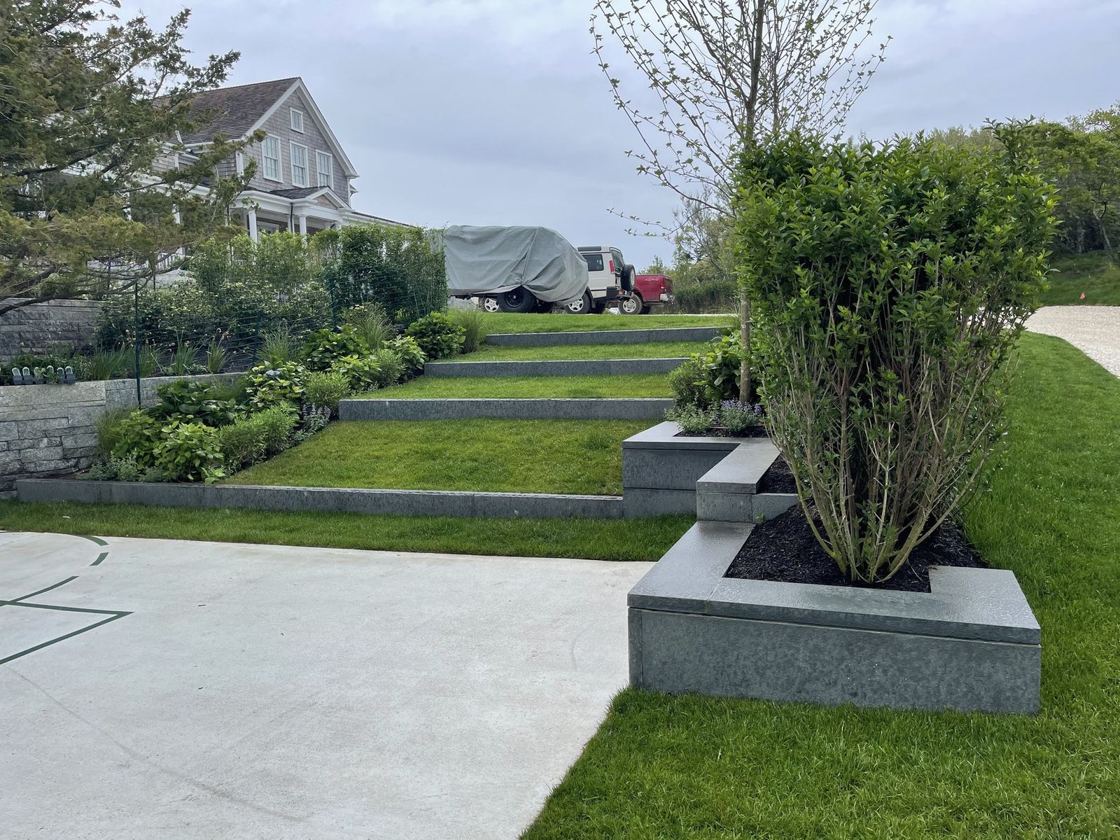 Terraced lawn steps with granite-edged planters and clipped shrubs