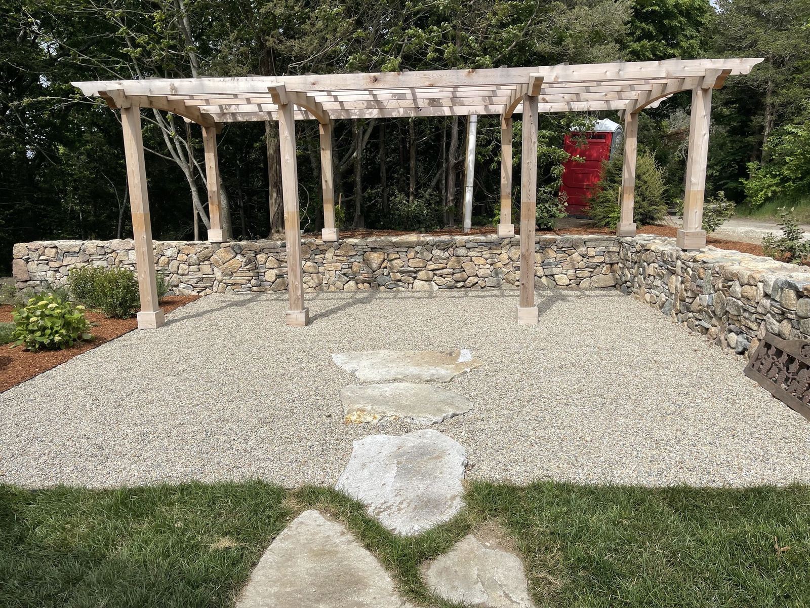 Timber pergola set on a hand-set fieldstone wall around a pea-stone outdoor room