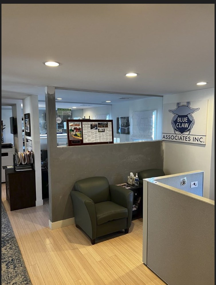 The Blue Claw Associates office lobby — green leather chair, the BCA crab logo on the wall, and Lawn & Landscape Top 100 magazine framed beside it